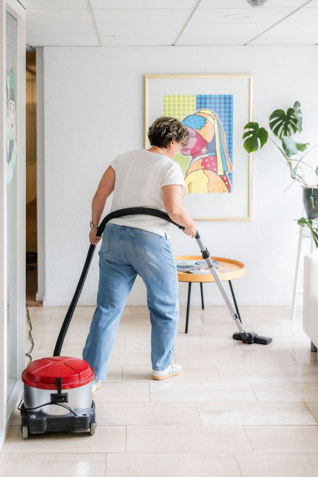 Medewerker huishoudelijke zorg stofzuigt met een sledestofzuiger